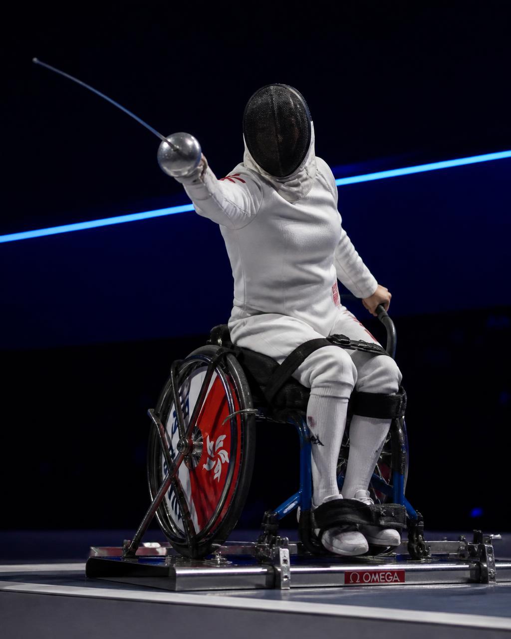 A wheelchair fencer lunging with an épée during a bout